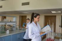 Женщина читает файл во время эксперимента в лаборатории — стоковое фото