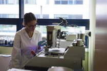 Estudiante adolescente usando maquinaria en laboratorio en la universidad - foto de stock