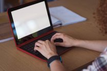 Imagen recortada de una estudiante universitaria usando un portátil en el escritorio en el aula - foto de stock