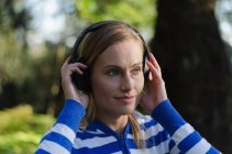 Крупним планом жіночий пішохід прослуховування музики, стоячи в лісі — стокове фото