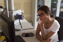 Teenager-Mädchen schaut auf Computer, während sie am Schreibtisch im Labor sitzt — Stockfoto