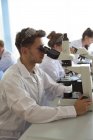 College students using microscope while practicing experiment in lab — Stock Photo