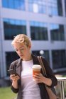 Studentin benutzt Handy beim Kaffee auf dem Campus — Stockfoto