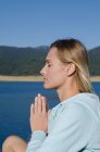Close up de caminhante feminino praticando postura de oração na margem do lago — Fotografia de Stock