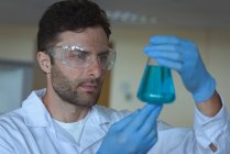 Estudiante universitario atento haciendo un experimento químico en laboratorio - foto de stock