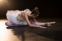 Female ballet dancer stretching before dancing in the studio — Stock Photo