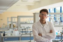 Портрет студента чоловічого коледжу з обіймами, схрещеними стоячи в лабораторії — стокове фото