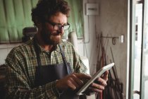 Aufmerksame Handwerker mit digitalem Tablet in Werkstatt — Stockfoto