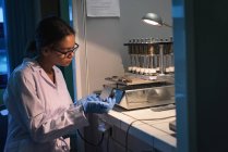 Studentin hält Ausrüstung in der Hand, während sie im Labor experimentiert — Stockfoto