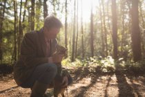 Mature man with his pet dog in forest — Stock Photo