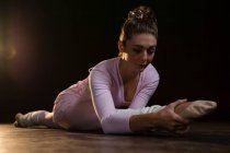 Bailarina de ballet femenina estirándose antes de bailar en el estudio - foto de stock