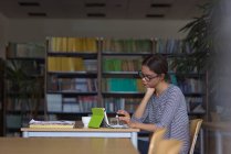 Studente universitaria femminile che usa tablet digitale mentre è seduta alla scrivania in classe — Foto stock