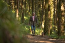 Älterer Mann geht mit Hund im Wald spazieren — Stockfoto
