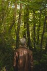 Вид ззаду вдумливого чоловіка, що стоїть у лісі — стокове фото