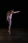 Ballet dancer posing on her tiptoe while rising a leg in studio — Stock Photo