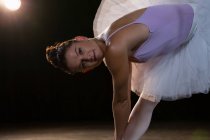 Retrato de bailarina de ballet femenina estirándose antes de bailar en el estudio - foto de stock
