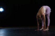 Ballerina performing stretching exercise in the stage — Stock Photo