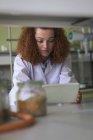 Teenage girl using digital tablet while standing by desk in lab — Stock Photo