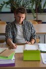 Angelo alto vista del giovane utilizzando tablet digitale mentre seduto alla scrivania in classe — Foto stock