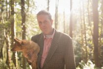 Portrait of man holding dog in forest on a sunny day — Stock Photo