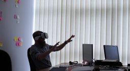 Ejecutivo usando auriculares de realidad virtual mientras trabaja en el escritorio en la oficina - foto de stock