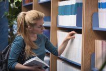 Студент университета выбирает книгу из библиотеки в колледже — стоковое фото