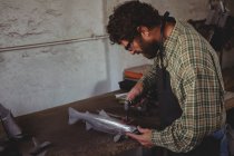 Attentive craftsman shaping a metal fish in workshop — Stock Photo