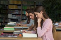 Estudiantes universitarios estudiando en el escritorio en el aula - foto de stock