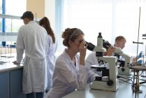 Estudiantes universitarios que practican experimentos científicos en laboratorio - foto de stock