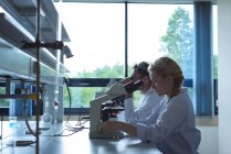 Universitätsstudenten experimentieren im Labor der Hochschule am Mikroskop — Stockfoto