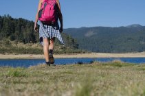 Low section of female hiker walking on field against mountain — Stock Photo