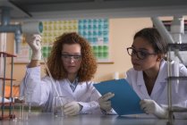 Estudiantes universitarias practicando química experimentan en el escritorio en el laboratorio - foto de stock