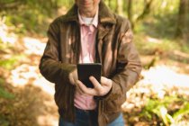 Meados de seção de homem tomando selfie com telefone celular na floresta — Fotografia de Stock