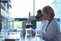 University students doing experiment on microscope in laboratory at college — Stock Photo
