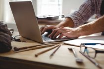 Mid section of craftsman using laptop at desk — Stock Photo