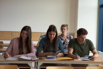 Young college students at desks by window in classroom — Stock Photo