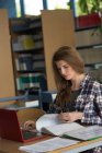 Young female student using laptop while studying at desk in classroom — Stock Photo