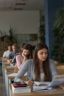 Студенты колледжа сидят за столом во время экзамена в классе — стоковое фото