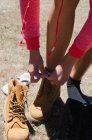 Vista ad alto angolo del laccio da scarpe da escursionista femminile in piedi sul campo — Foto stock