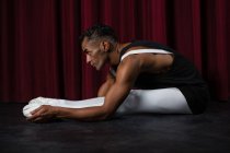 Балерино выполняет упражнения на растяжку на сцене — стоковое фото