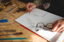 Mid-section of craftsman drawing sculpture design in workshop — Stock Photo