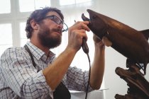 Artesano trabajando en la escultura de peces en el taller - foto de stock