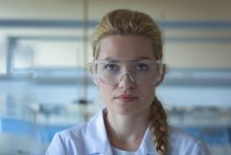 Retrato de estudiante universitario en gafas protectoras en laboratorio - foto de stock