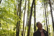 Nachdenklicher reifer Mann steht im Wald — Stockfoto