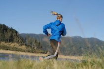 Rückansicht einer Athletin, die bei strahlend blauem Himmel auf dem Feld läuft — Stockfoto