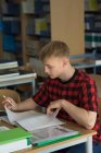 High angle view of young male student studying at desk in classroom — Stock Photo