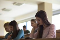 Low angle view of young college students at desk while sitting classroom — Stock Photo