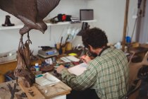 Handwerker zeichnet Skulptur-Design in Werkstatt — Stockfoto