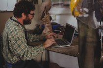 Attentive craftsman using laptop in workshop — Stock Photo
