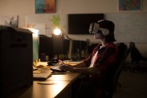 Виконавчий з використанням гарнітури віртуальної реальності під час роботи за столом в офісі — стокове фото